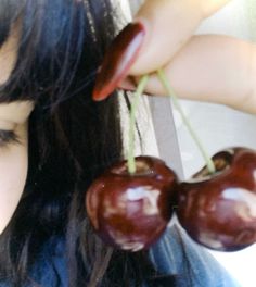 a close up of a person holding three cherries