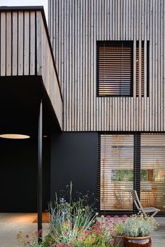 the house is made out of wood and has plants growing in pots on the front lawn