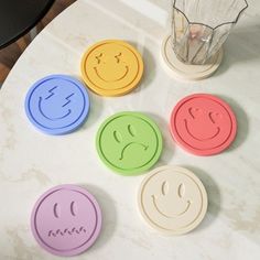 four smiley face coasters sitting on top of a table next to a blender