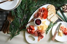 an assortment of cheeses, meats and crackers on a platter