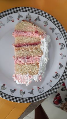 a piece of cake on a plate with white frosting and pink icing, sitting on a table