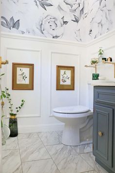 a white toilet sitting in a bathroom next to a wall with flowers painted on it