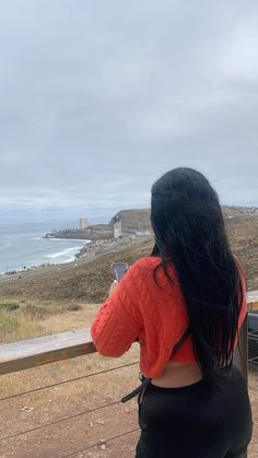 a woman looking out at the ocean from a balcony with her back to the camera