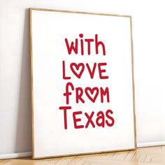 a white framed poster with the words love from texas written in red on it next to a wooden floor