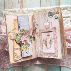 an open book with flowers and lace on the pages, sitting on top of a wooden table