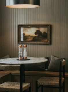 a table with two bottles on it in front of a painting and some stools