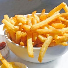 french fries in a white bowl with ketchup on the side