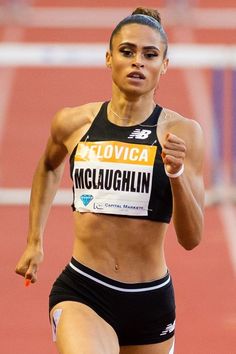 a woman running on a track in a black and white outfit with her hands behind her back