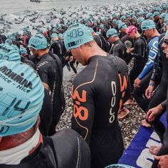 a large group of men in wetsuits standing next to each other