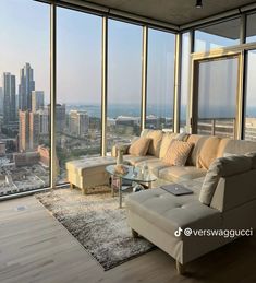 a living room filled with furniture and large windows overlooking the cityscape in the distance