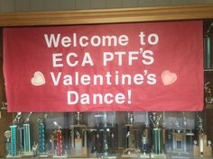 a sign that says welcome to eca ptfs valentine's dance in front of bookshelves