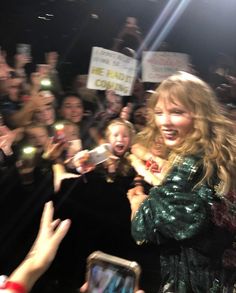 a group of people holding up cell phones and taking pictures with their hands in the air