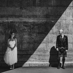 a man in a kilt standing next to a woman wearing a dress and holding a bouquet