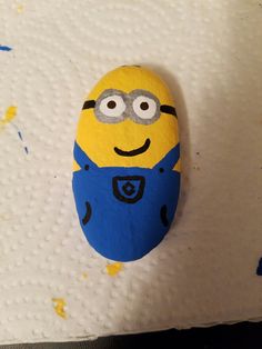 a rock painted like a minion with eyes on it sitting on top of a sheet of paper