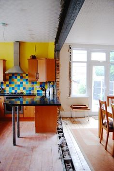 a kitchen with yellow and blue tiles on the walls