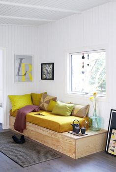 a living room filled with furniture and pillows on top of a wooden table next to a window