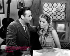 a man and woman standing next to each other in front of a desk with music sheets on it