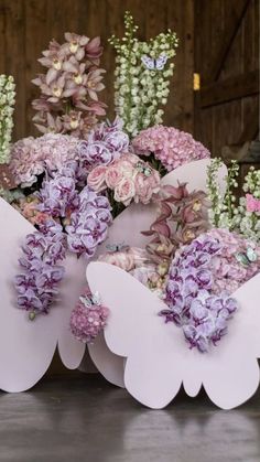 a bunch of flowers that are sitting on the ground in front of each other with butterfly wings around them