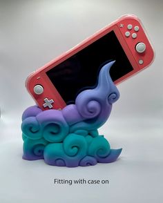 a nintendo wii game controller sitting on top of a cloud like object with an elephant figure next to it