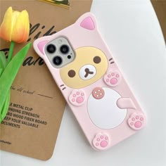 a pink phone case with a cat on it next to a yellow tulip flower