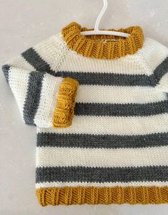 a knitted sweater hanging on a clothes hanger with the tag attached to it