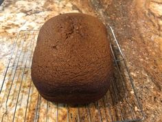 a loaf of chocolate cake sitting on top of a cooling rack