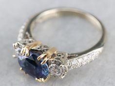 an engagement ring with a blue stone surrounded by white and yellow gold diamond trimmings