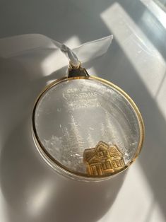 a glass ornament with a house on it and a ribbon around the edge