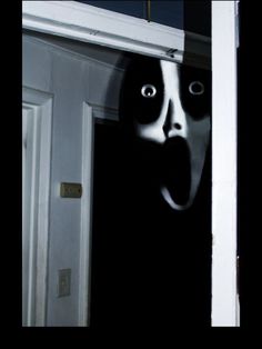 a creepy mask hanging from the side of a door