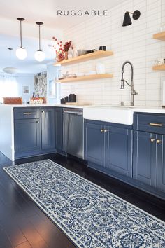 a kitchen with blue cabinets and rug on the floor in front of the sink area