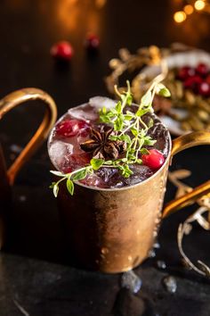 a copper mug filled with ice and garnished with cranberries, pine cones and sprigs