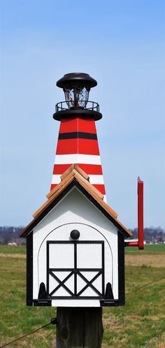 a red and white lighthouse on top of a wooden post