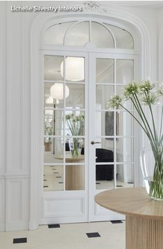 a vase filled with flowers sitting on top of a table in front of a doorway