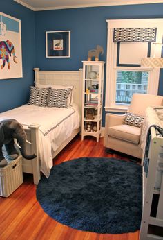 a bedroom with blue walls and wooden floors, an elephant toy on the floor in front of the bed