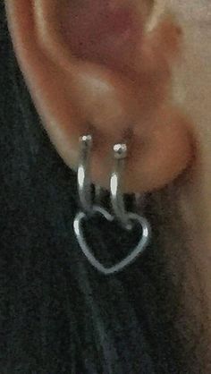 a close up of a person wearing ear rings with a heart on the middle of them