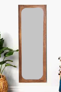 a mirror sitting on top of a table next to a potted plant and vase