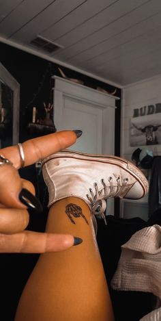 a woman's leg with tattoos on it and her fingers pointing at the camera