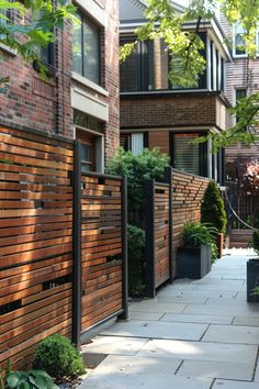 a wooden fence next to a building with plants growing on the side and in front