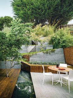 an outdoor dining area with table and chairs next to a small pond in the backyard