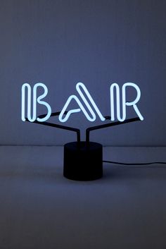 a neon sign with the word bar on it's stand in front of a wall