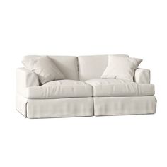 a white couch with two pillows on it's back and one arm folded down