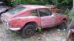 an old rusted out car sitting in the woods