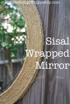 a mirror that is on top of a wooden fence with the words sisal wrapped in rope