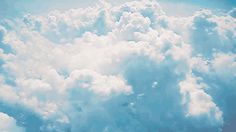 an airplane is flying high in the sky above some clouds and blue sky with white fluffy clouds