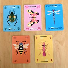 four playing cards with different designs on them sitting on top of a wooden table next to each other