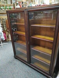 an antique display case with glass doors and shelves in the middle of a store aisle