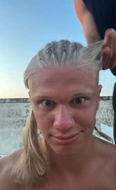 a woman with blonde hair and braids on her head is looking at the camera