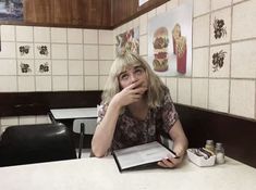 a woman sitting at a table with a book in front of her and looking up