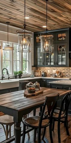 a large kitchen with wooden floors and black cabinets, along with lots of counter space