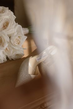 a bouquet of white roses sitting on top of a table next to a pair of shoes